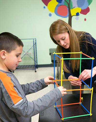Special Education teacher and elementary student work together at a school to build a structure
