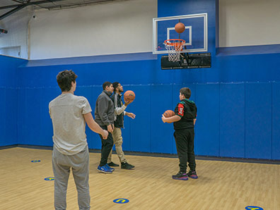 Four high school boys play basketball in the gym at a special education school.