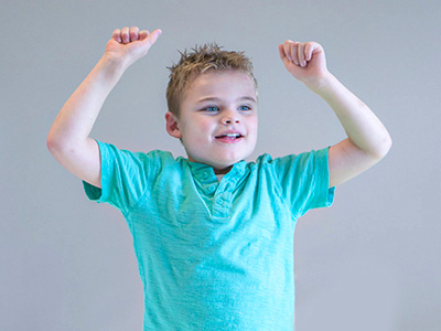 Elementary school special education boy with raised arms is happy to be at New Story Schools.
