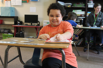 A special education elementary school student looks up from his desk while working on his lesson
