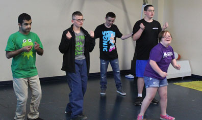 A class of high school special education students dances in the gym
