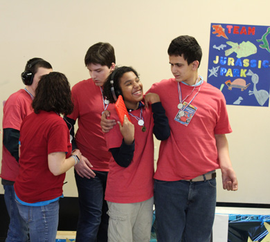 A group of students in an autism support program smile as they work on a project together.