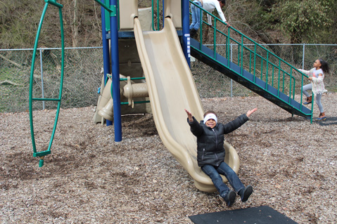 Students in an autism support program smile from the playground of their special education school