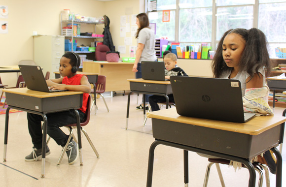 Students in a special education look down at laptops as they complete their coursework