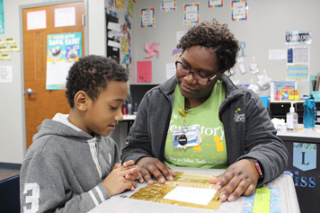 A special education teacher works with an elementary school boy on his assignment