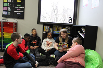 A group of emotional support students gather around their special education teacher in the school library.