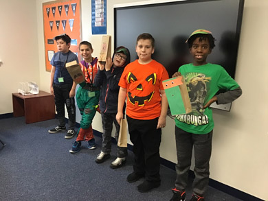 Five students in an emotional support classroom smile in Halloween themed clothes.