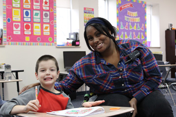 An elementary school boy in an emotional support program smiles with his special education teacher