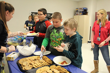 Special education students gather cookies from a table at their school.