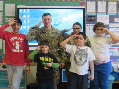 Four boys from a special education class and their teacher salute with a member of the armed forces who visited. 