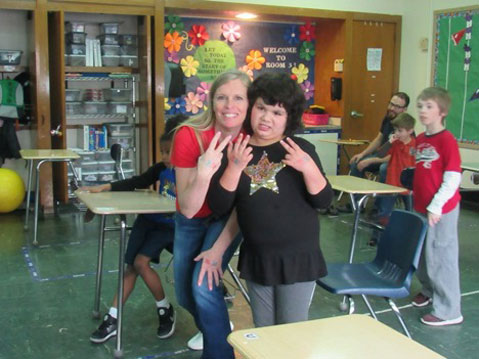 A young girl from an autism support classroom smiles with her special education teacher
