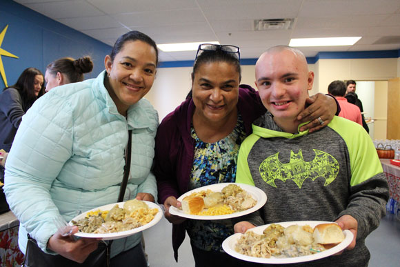 Special education student and family smile with plates of food at a school event. 