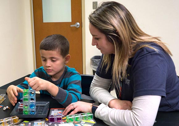 A young boy and his special education teacher put together blocks.