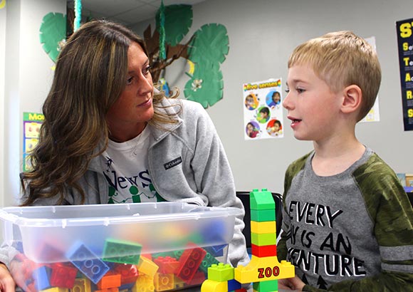 A special education teacher and students work with blocks together.