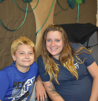 A special education student and teacher smile together in their classroom.
