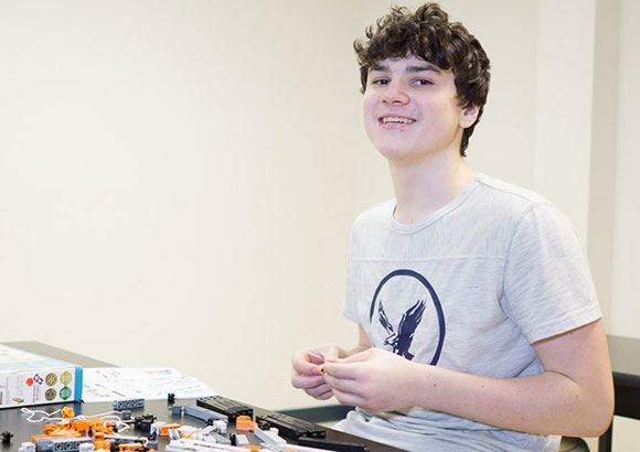 Smiling high school boy assembles blocks as part of his sensory program at a special education high school.