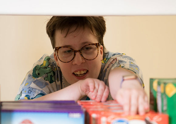 Special education teen girl, in the Transition program, stocking shelves as part of developing life skills.