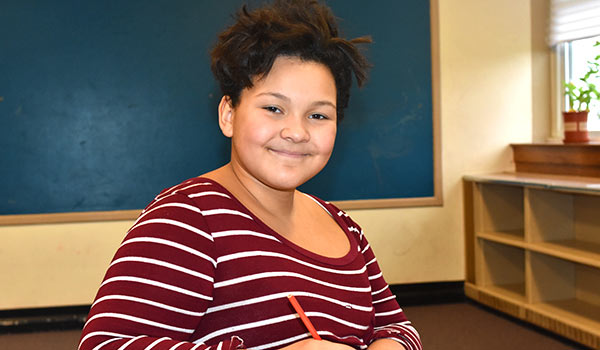 A special education student looks thoughtfully at a worksheet she is completing.