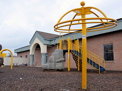 Yellow playground equipment sits in front of a New Story Schools location.