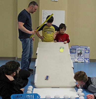 Four students watch an activity using a ramp with their special education teacher.