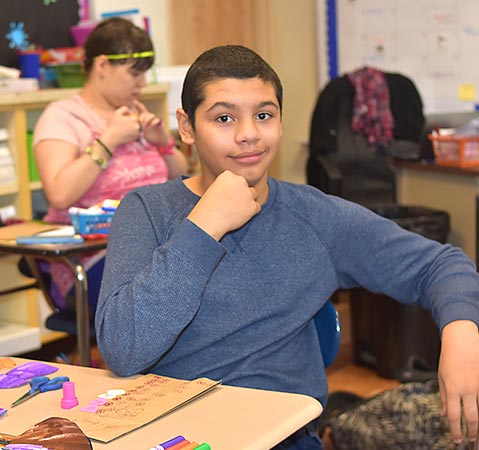 A high school boy in a blue shirt smiles for the camera.