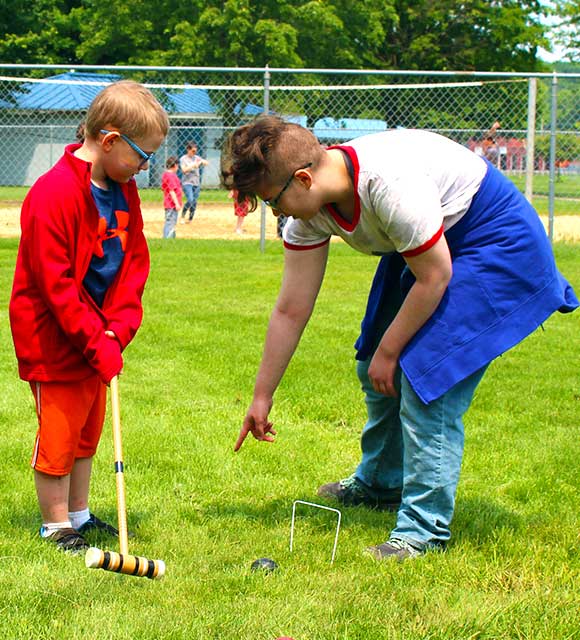 Two students at a special education school play croquet together during a picnic.