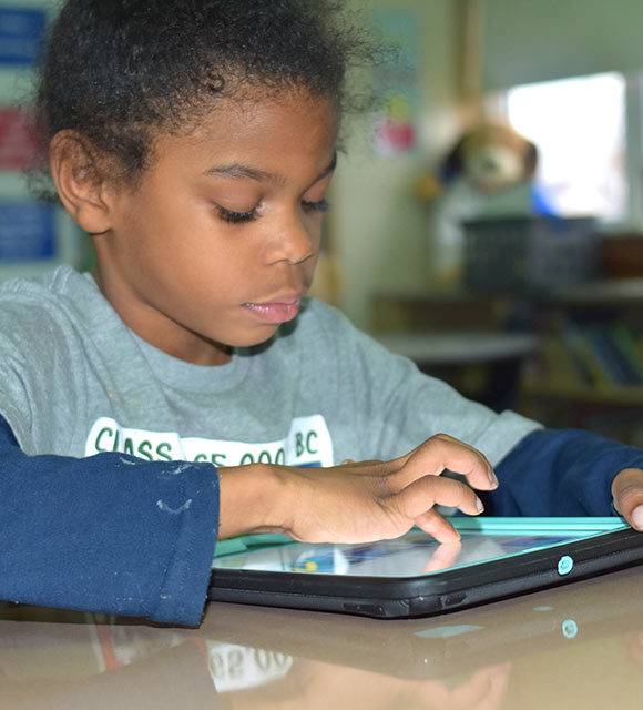 An elementary student works with an assistive device in her special education school.