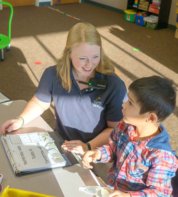 Special education teacher providing education lesson on days of the week to elementary school boy with autism.