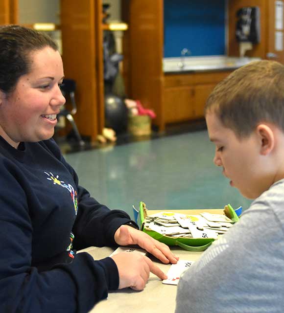 A special education teacher smiles at her student during a lesson.
