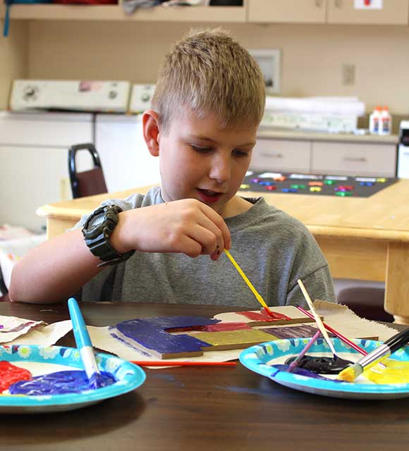 An elementary school boy uses paints during a lesson at his special education school.