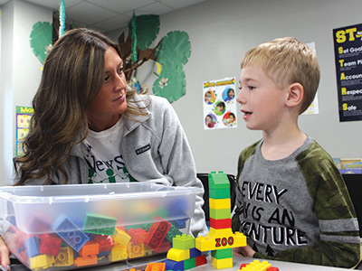 A special education teacher and students work with blocks together.