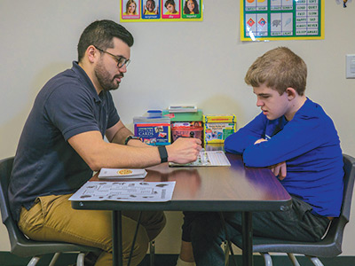 Special education middle school boy pronouncing sentences with a speech therapist.