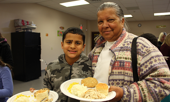 Male Student and Grandmother hold their plates of thanksgiving food.