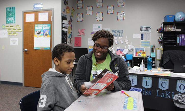 Teacher works with young student. They read a book titled, "Ruby Bridges" together. 