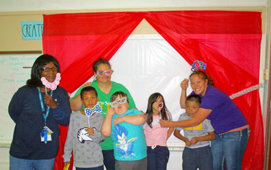 Three staff members at a special ed school play dress up with young students