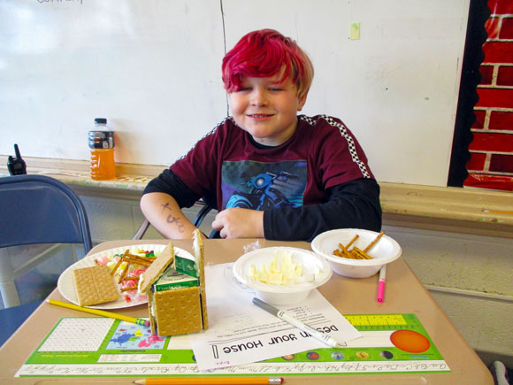 A young boy in his special education classroom builds a gingerbread house