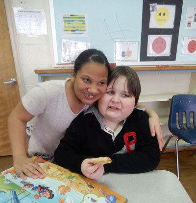 Special education teacher and student smile together while working on a project