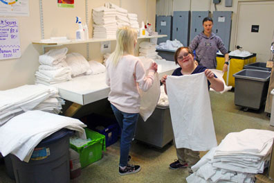 A young girl folds towels on a field trip from her special education school