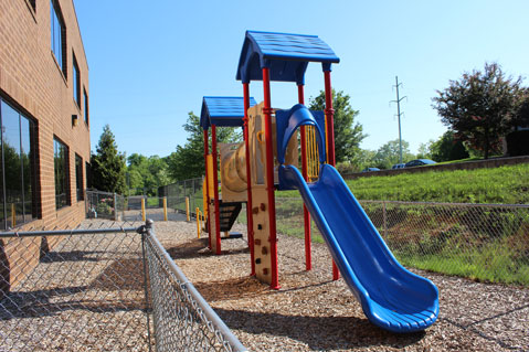 A blue slide and playground equipment stand ready outside a special needs school