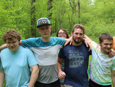 A special education teacher guides several high students on their walk through the park.