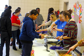 Students, staff, and families line up for a Thanksgiving buffet at a special needs school.