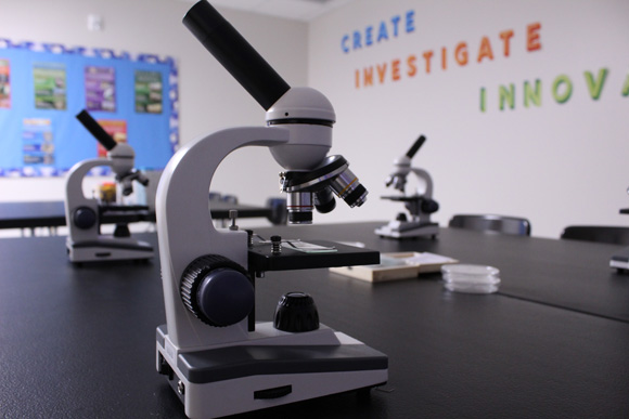A grey microscope sits ready for use in the STEAM room of a special education school.