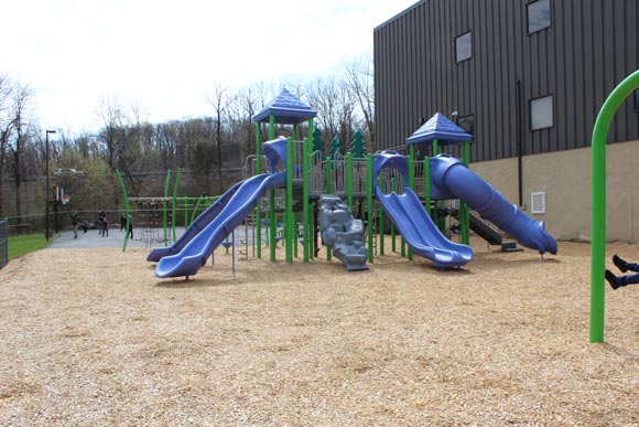 A blue slide and playground equipment stand ready outside a special needs school