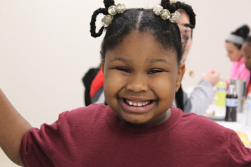 An elementary school girl smiles for the camera in her special needs school.