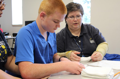A special education teacher helps a young boy practice motor skills.