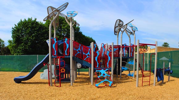 A blue slide and playground equipment stand ready outside a special needs school