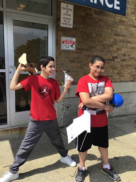 Two young boys smile in front of the doorway of their special education school.