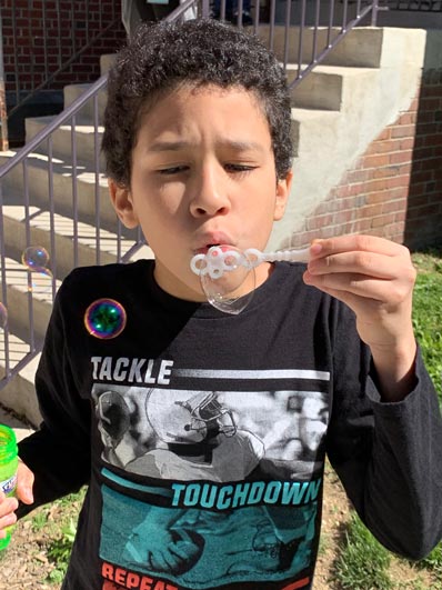 A special education student wearing a black shirt blows bubble