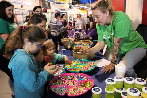 Young girls dig through beads as their special education teachers look on.