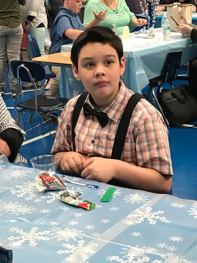 A young boy in a bow tie watches during an event at his special education school.